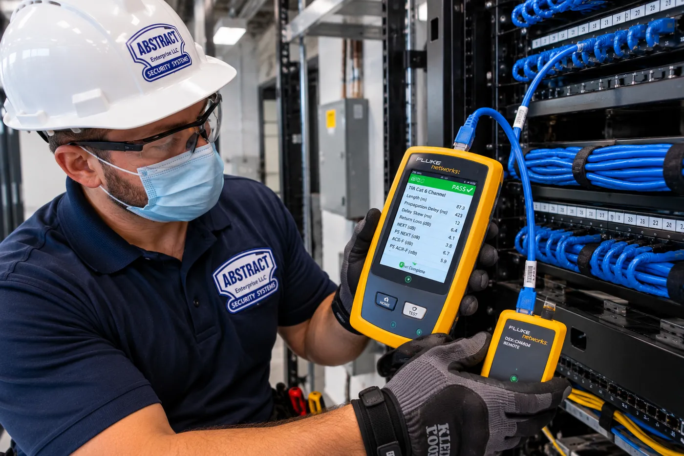 AESS technician holding a cable certifier showing a passing Cat6 channel test at a network rack in the Hudson Valley