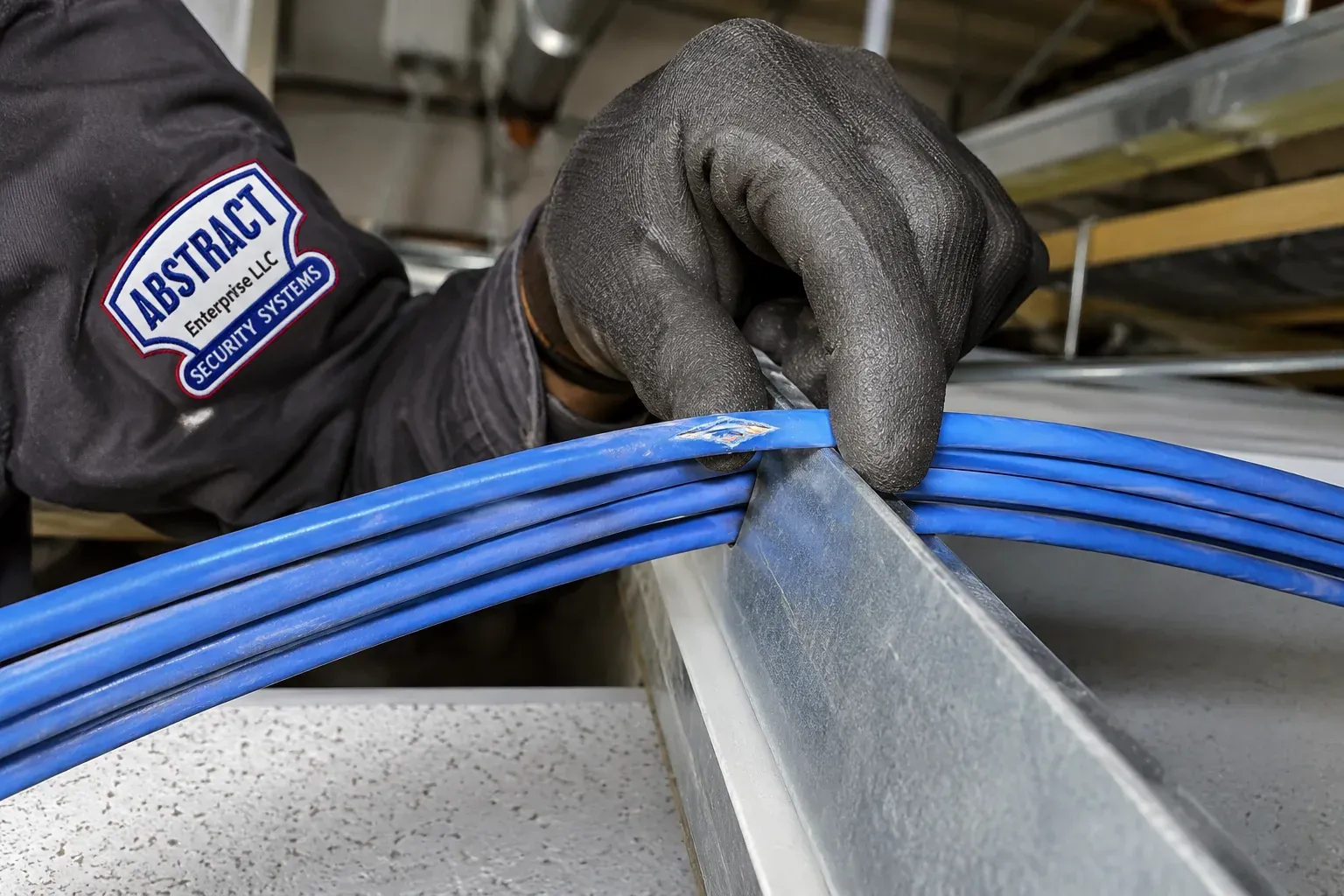 Nicked Cat6 jacket on a metal edge — Cat6 repair Nassau County Gloved hand lifting a bundle of blue Cat6 cables off a sharp sheet-metal edge above a ceiling grid, one jacket visibly nicked, Cat6 repair Nassau County