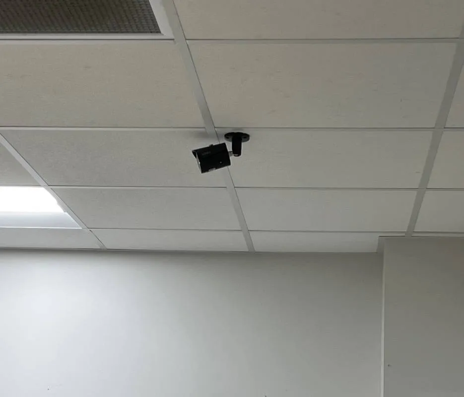 Black bullet camera on a short pendant mount fixed through a white ceiling tile — reference photo from another AESS job, Cat6 repair page for Tottenville, Staten Island