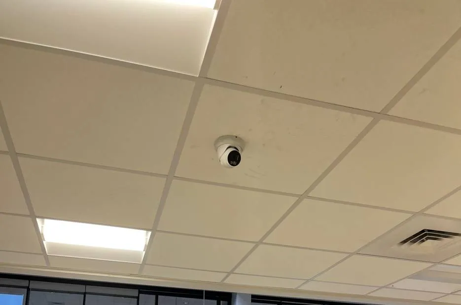 Small dome camera on a lay-in ceiling tile between a light panel and an air vent — reference photo from another AESS job, Cat6 repair page for Tottenville, Staten Island