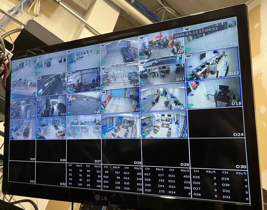 Recorder monitor showing a grid of camera tiles above a per-channel bitrate table, with network cable bundles at the left edge — reference photo from another AESS job, Cat6 repair page for Tottenville, Staten Island
