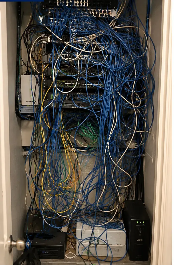 Tangled closet before cleanup — Port Morris, Bronx inherited cabling Network closet crowded with tangled blue, white and yellow cables over older switches before cleanup, Port Morris, Bronx inherited wiring