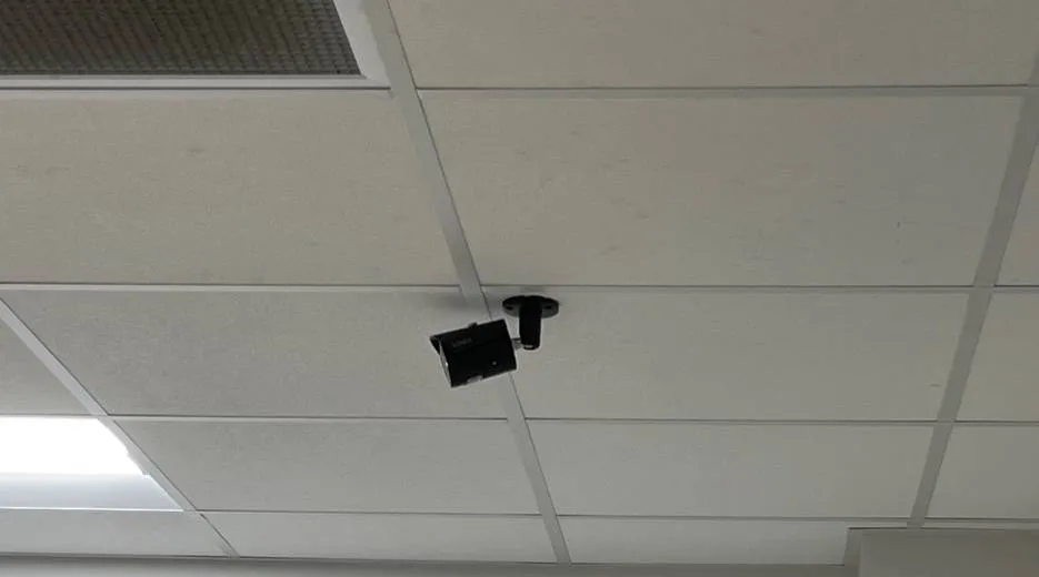 Black bullet camera on a short ceiling mount, Ulster County office example photo Hikvision camera installation Ulster County office example: small black bullet camera on a short ceiling mount in a white drop-ceiling grid