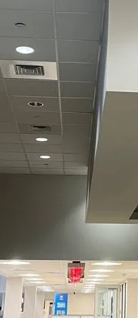 Long tiled ceiling run toward a far exit sign, Ulster County example photo Hikvision cable run planning Ulster County example: long tiled ceiling corridor with air vents and recessed lights leading to a far red exit sign