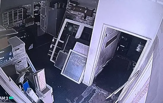 One recorder tile showing a dim back storeroom, Ulster County example photo Hikvision recorder view Ulster County example: one camera tile on a recorder screen showing a dim back storeroom with stacked frames and an open doorway