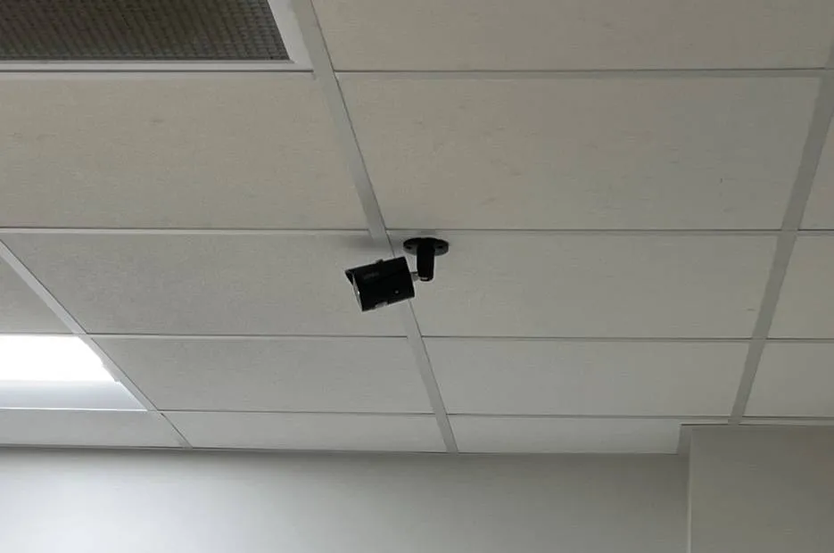Bullet camera on a short ceiling mount β example for Queens attendant booths and offices Queens parking lot camera example photo: a black bullet camera on a short mount fixed to a dropped ceiling between tiles