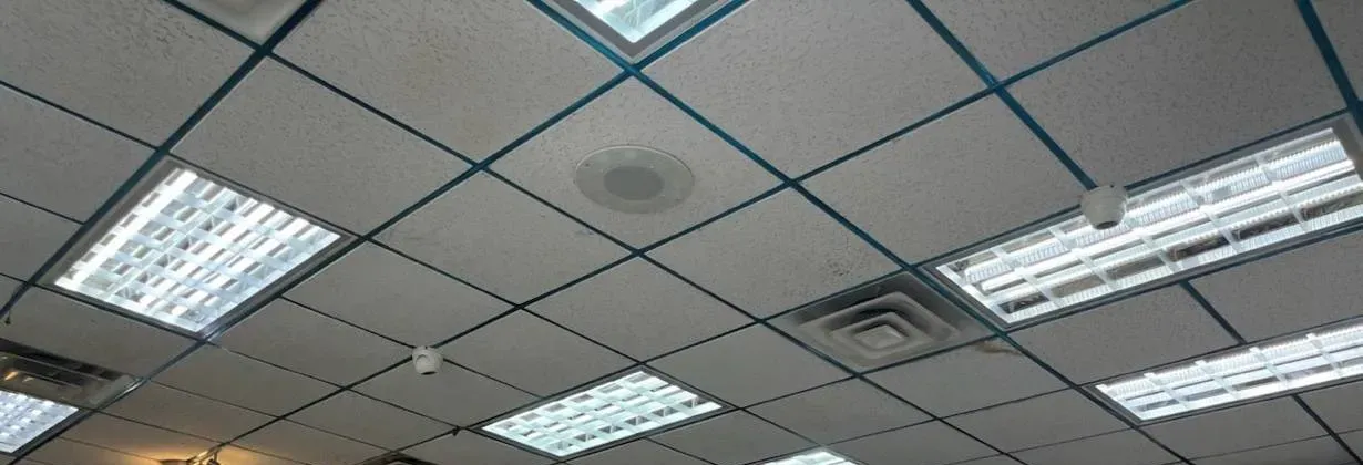 Mini dome cameras spaced across a drop ceiling — example photo for Orange County school corridors and cafeterias Orange County school security camera installation example photo: a wide drop ceiling with fluorescent light panels and small mini dome cameras set into the tile grid at intervals
