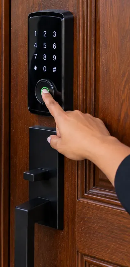 Fingerprint sensor on a keypad deadbolt — Great Kills, Staten Island Fingertip on the green-lit fingerprint sensor of a keypad deadbolt on a wood-grain door, black handleset below — fingerprint smart lock, Great Kills, Staten Island