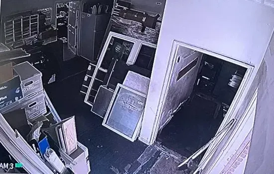 Dim recorder view of a crowded back storeroom â Manhattan Smart PSS support example Manhattan Smart PSS support example photo: a dim recorder camera view of a crowded back storeroom with stacked boxes, leaning frames and an open doorway to a darker room