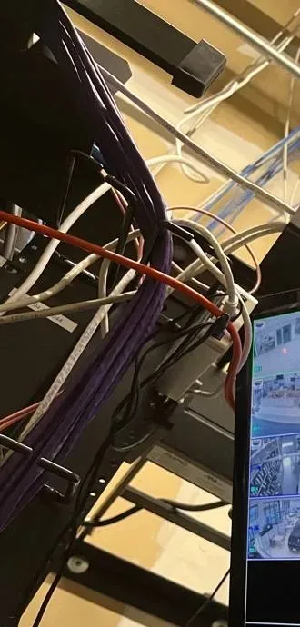 Purple network cable bundle dropping beside an equipment rack â Manhattan Smart PSS support example Manhattan Smart PSS support example photo: a thick bundle of purple network cables with white, red and black patch cords dropping past the side of an equipment rack, the edge of a camera monitor at the right