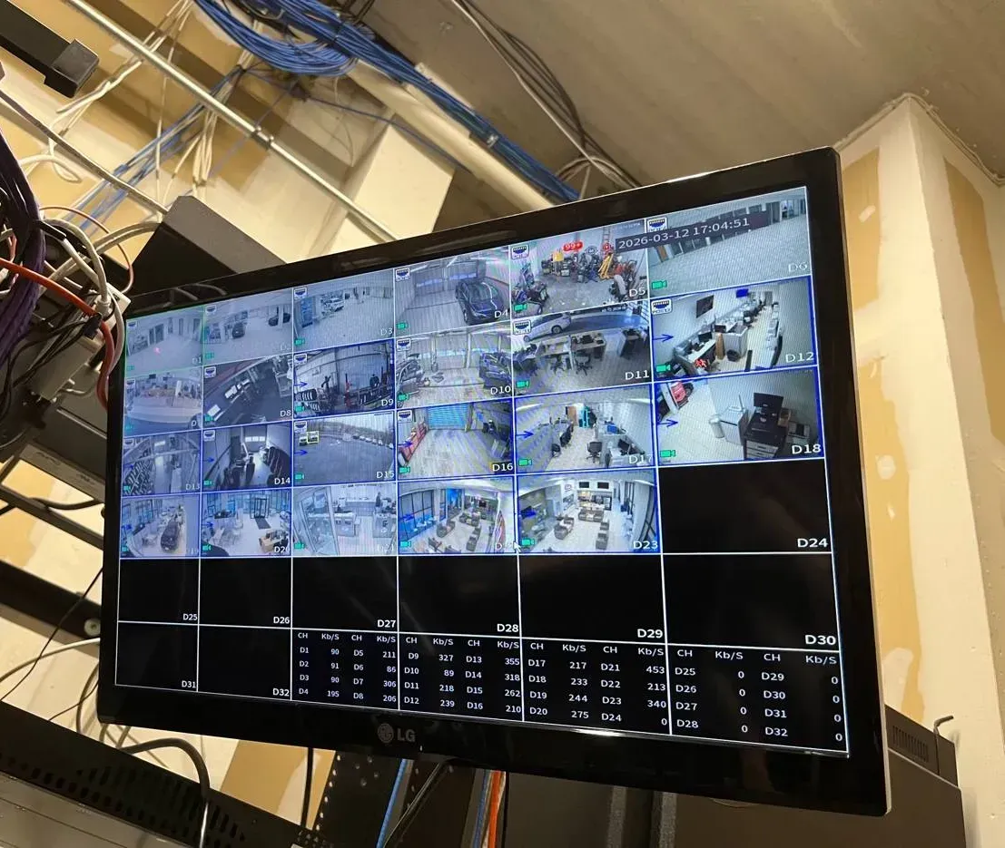 Recorder monitor with a 32-tile camera grid under ceiling cable runs â Manhattan Smart PSS support example Manhattan Smart PSS support example photo: a wall-hung LG monitor showing a recorderâs 32-tile camera grid and a per-channel bitrate table, below bundles of blue and white network cable at the ceiling