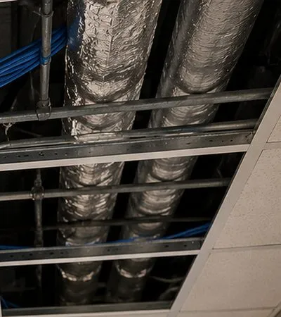 Sonos installation Battery Park City, Manhattan: two silver foil-wrapped air ducts running above an open suspended-ceiling grid, with a strand of blue cable along the metal runners