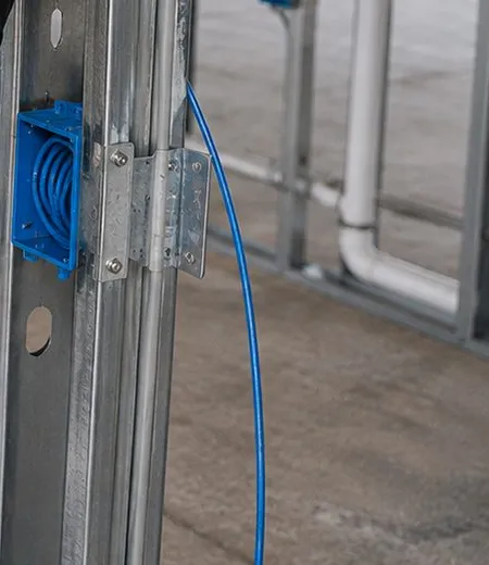 Blue box and cable on a bare stud — Greenwich Village, Manhattan Sonos installation Sonos installation Greenwich Village, Manhattan: a blue electrical box filled with coiled blue cable fixed to a bare metal stud, the cable running down to a concrete floor in an open renovation