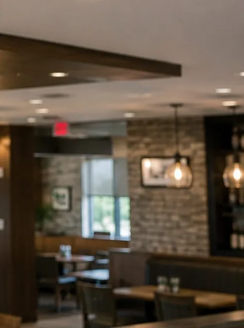 Dining room with stone-clad walls and pendant lights — Riverdale, Bronx Sonos installation Sonos installation Riverdale, Bronx: dining room with stone-clad walls, glass pendant lights and wooden tables