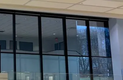 Black-framed glass wall below a ceiling edge — reference photo, Sonos installation St. George, Staten Island St. George, Staten Island Sonos installation reference photo: wall of tall glass panes in black frames below the edge of a tiled ceiling, with bare trees outside