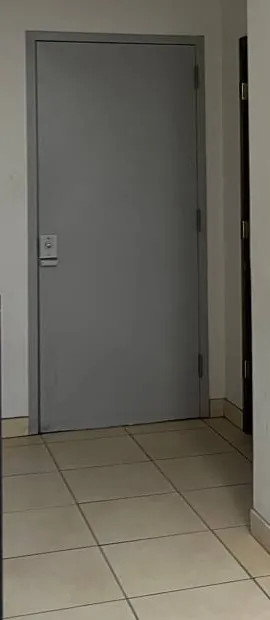 Grey steel door at the end of a tiled passage — reference photo, Sonos installation St. George, Staten Island St. George, Staten Island Sonos installation reference photo: plain grey steel door with a small keypad lock at the end of a narrow passage with a beige tiled floor