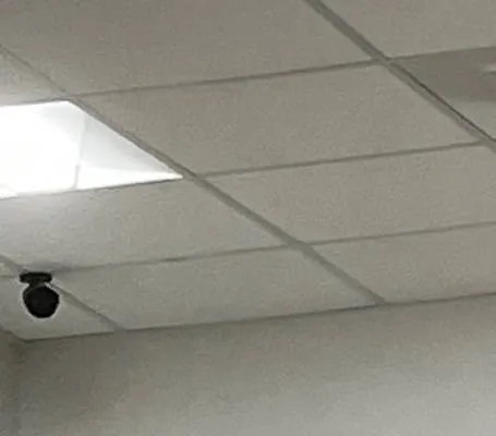 Grid ceiling, light panel and a small black dome — reference photo, Sonos installation St. George, Staten Island St. George, Staten Island Sonos installation reference photo: suspended grid ceiling with a glowing square light panel and a small black dome device near the wall