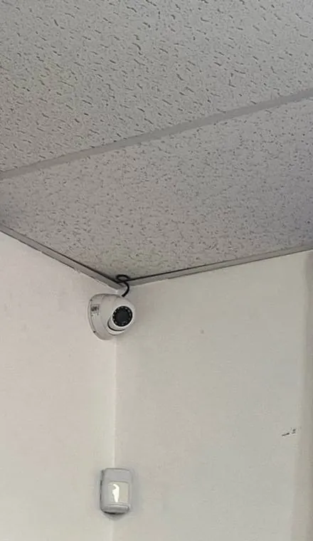 Dome and wall sensor in a textured-ceiling corner — reference photo, Sonos installation St. George, Staten Island St. George, Staten Island Sonos installation reference photo: white dome device tucked into the corner under a textured tile ceiling, with a small white sensor on the wall below