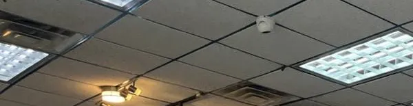 Throgs Neck, Bronx Sonos installation reference photo: dark-gridded drop ceiling with square light panels, a small white dome device and track spotlights