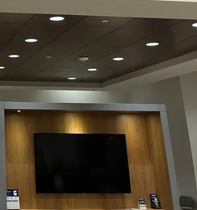 Throgs Neck, Bronx Sonos installation reference photo: black flat-screen TV mounted in a wood-panelled wall niche under a dark ceiling panel with recessed downlights