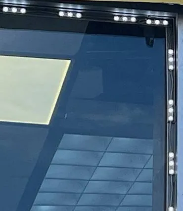 LED-lined storefront window frame — AESS reference photo for Sonos on the Upper West Side, Manhattan Upper West Side, Manhattan Sonos reference photo: dark storefront window frame edged with small white LED lights, a ceiling grid reflected in the glass