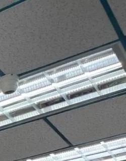 Shop light panels and a small white dome โ reference photo, Sonos installation Williamsburg, Brooklyn Williamsburg, Brooklyn Sonos installation reference photo from another AESS job: long fluorescent light panels in a teal grid ceiling with a small white dome device