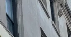 Upper windows and cornice of a stone building โ reference photo, Sonos installation Williamsburg, Brooklyn Williamsburg, Brooklyn Sonos installation reference photo from another AESS job: upper windows and a carved cornice bracket on the stone face of a pre-war corner building