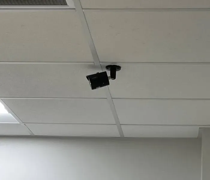 Black bullet camera on a drop-ceiling mount β Putnam County Ubiquiti business example Putnam County Ubiquiti business installation example photo: a black bullet camera on a short black mount fixed to a white drop-ceiling grid