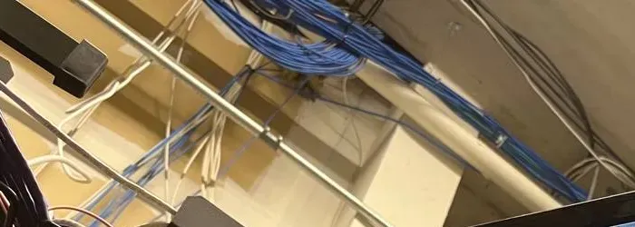 Network cable bundles along a ceiling pipe — Dutchess County Uniview installation cabling example Blue and white network cables running along a ceiling pipe, the kind of home-run cabling behind a Dutchess County Uniview installation