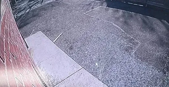 Playback frame along a brick wall to a paved lot — Uniview camera installation Dutchess County example Recorder playback image along a red brick wall toward a paved lot, showing how a Dutchess County Uniview camera frames an approach