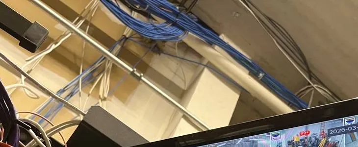 Video wall installation Long Island example photo: bundles of blue and white network cable running along a ceiling pipe and structure above the top edge of a display