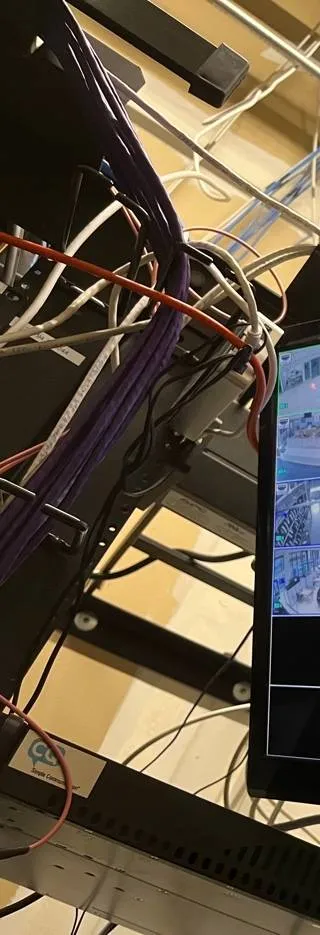 Video wall installation Long Island example photo: purple, white and red patch cables running down the side of an equipment rack next to the edge of a monitor